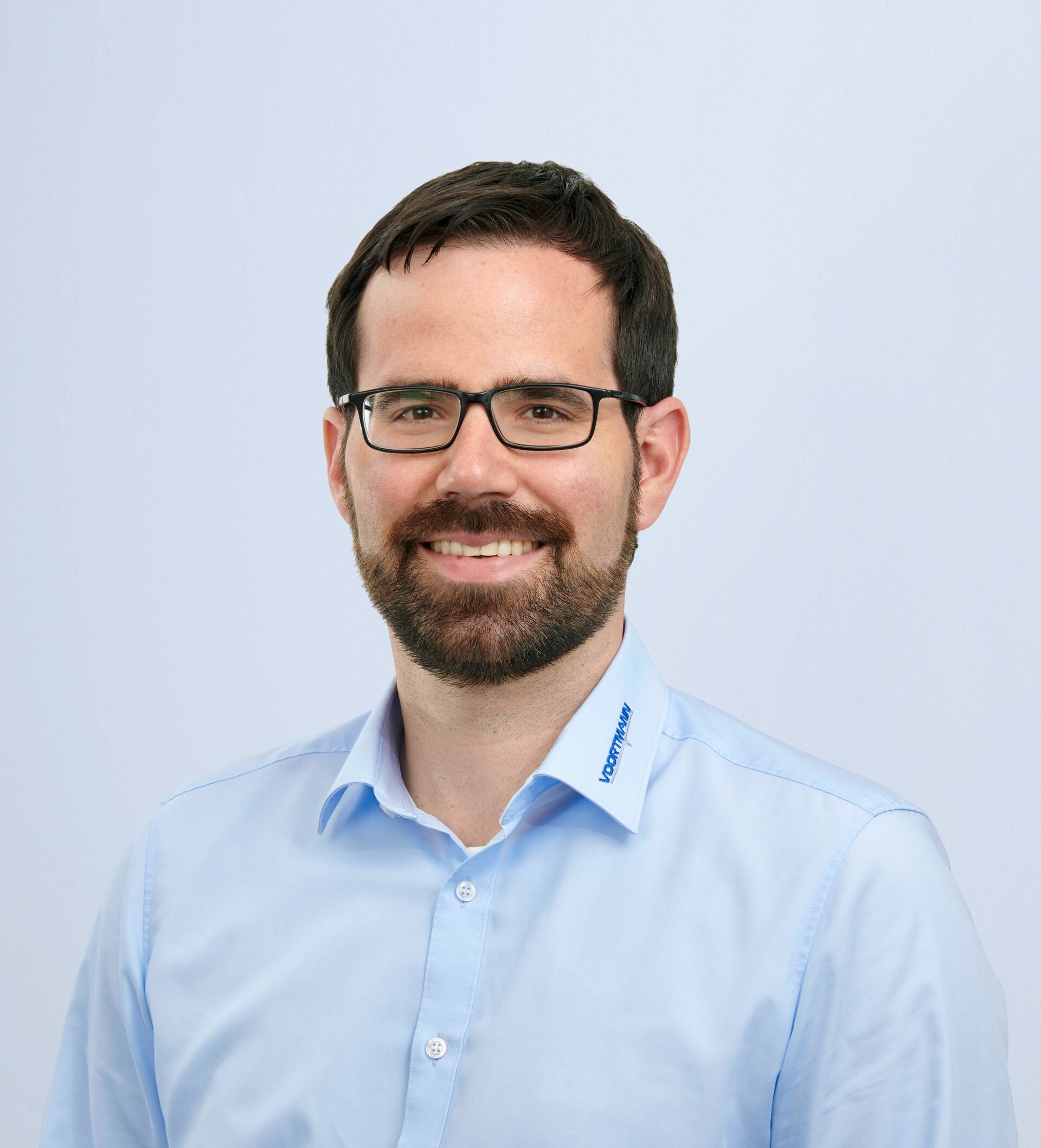 Porträt von Christian bei VOORTMANN vor blauem Hintergrund